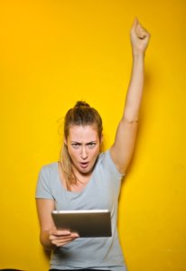 Woman holding an iPad and raising her fist triumphantly